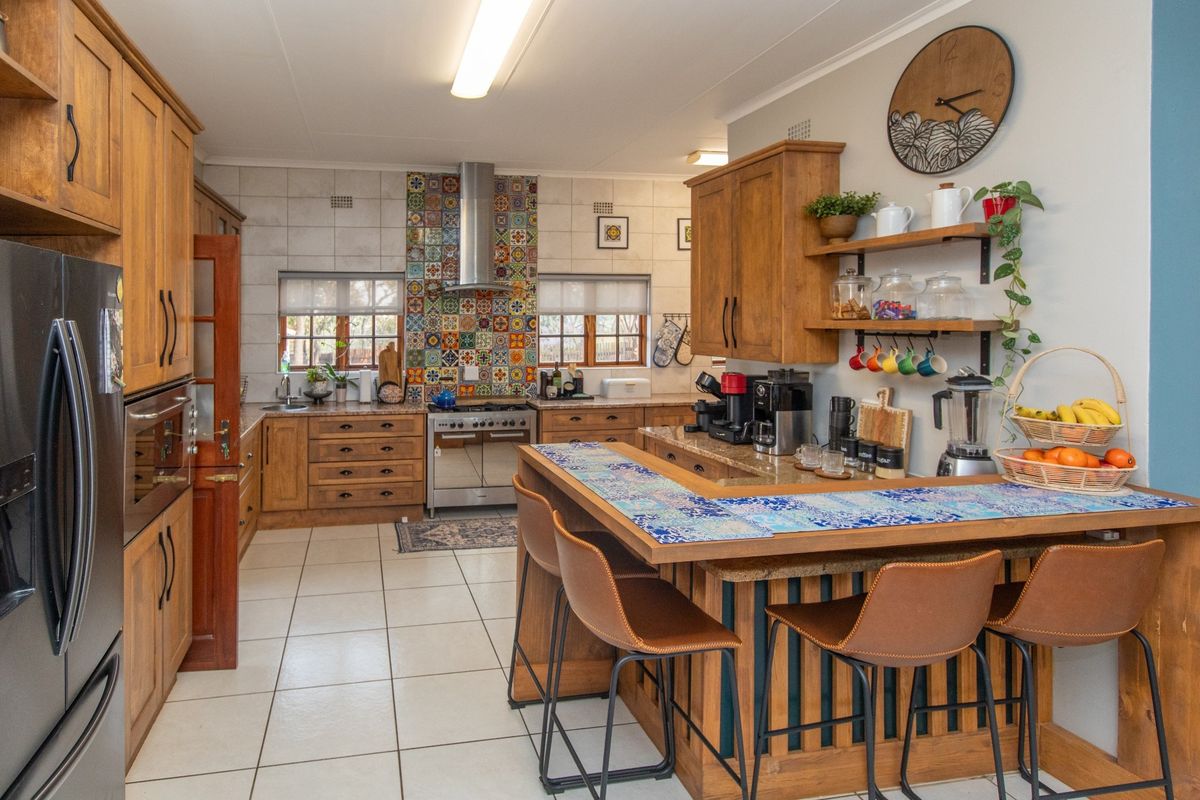 A spacious kitchen featuring warm wooden cabinetry, granite countertops, a breakfast bar, and a decorative tiled backsplash with a stainless steel gas stove.