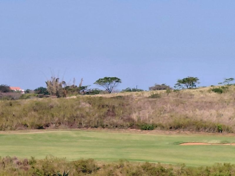 A scenic view of a golf course fairway featuring a sand bunker and natural landscape surroundings.