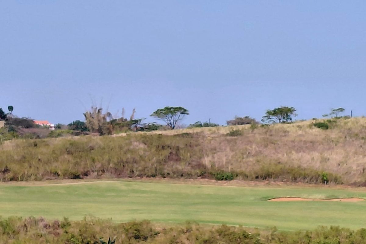 A scenic view of a golf course fairway featuring a sand bunker and natural landscape surroundings.