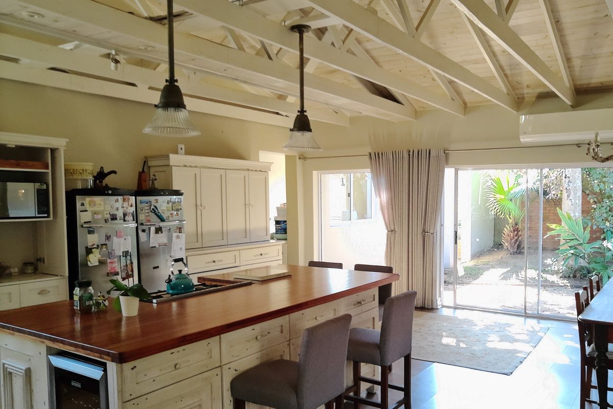 Spacious kitchen featuring a large timber-topped island, exposed vaulted ceiling beams, and direct access to the rear garden through sliding glass doors.