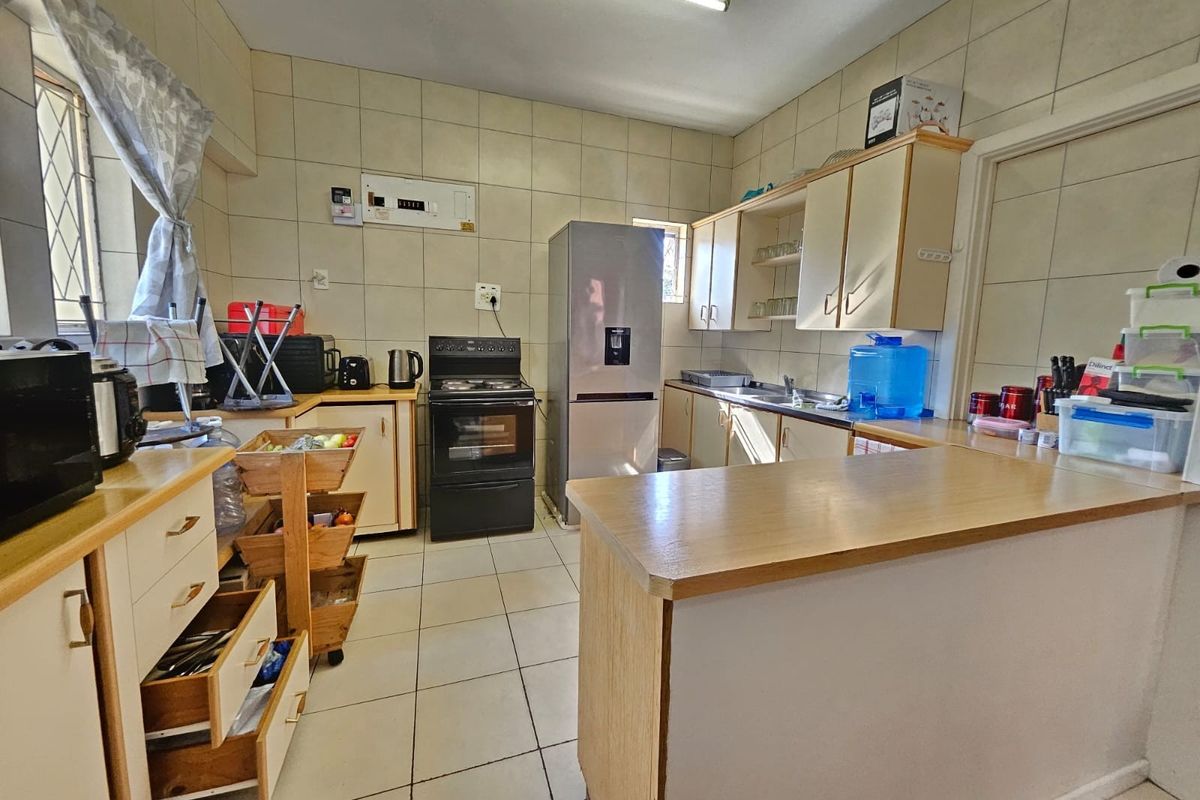 Functional kitchen featuring tiled walls and floors, laminate countertops, built-in cabinetry, and a freestanding stove, offering a practical layout for daily use.