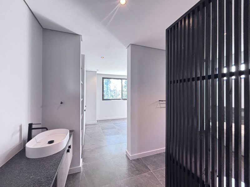 Modern bathroom featuring a sleek vessel sink, stone vanity, and a contemporary slatted timber privacy screen, finished with high-quality floor tiling.