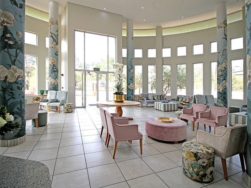 Spacious and elegant clubhouse lounge featuring high ceilings, large windows, decorative columns, and tiled flooring, providing a bright and welcoming communal area.