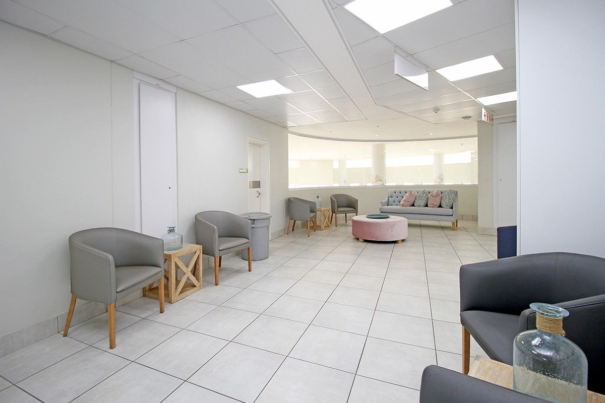 A bright and spacious communal lounge area featuring neutral tiled flooring and recessed ceiling lighting, suitable for a retirement village common space.