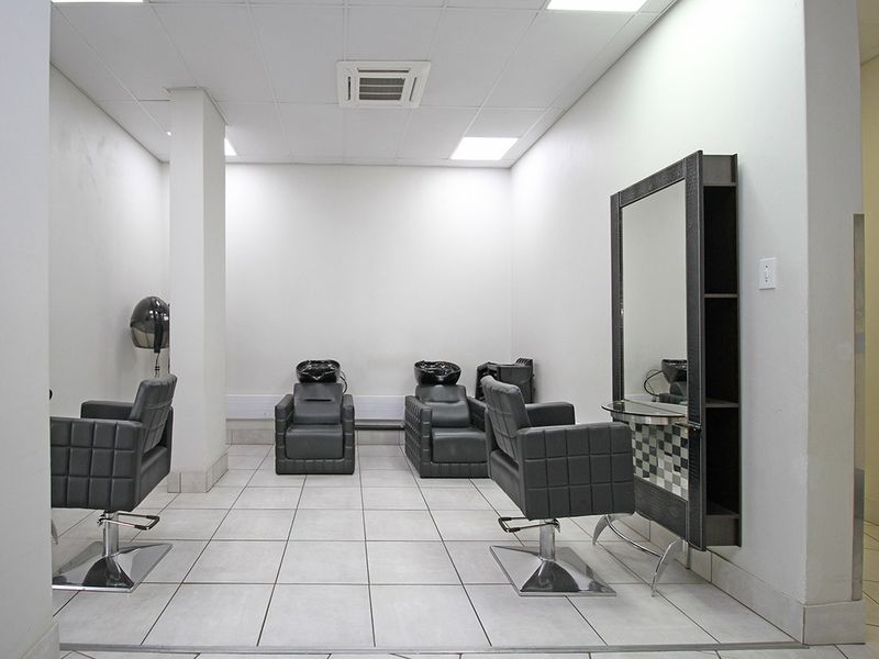 A well-maintained salon or utility space featuring tiled flooring, recessed ceiling lighting, and integrated air conditioning, suitable for professional use.