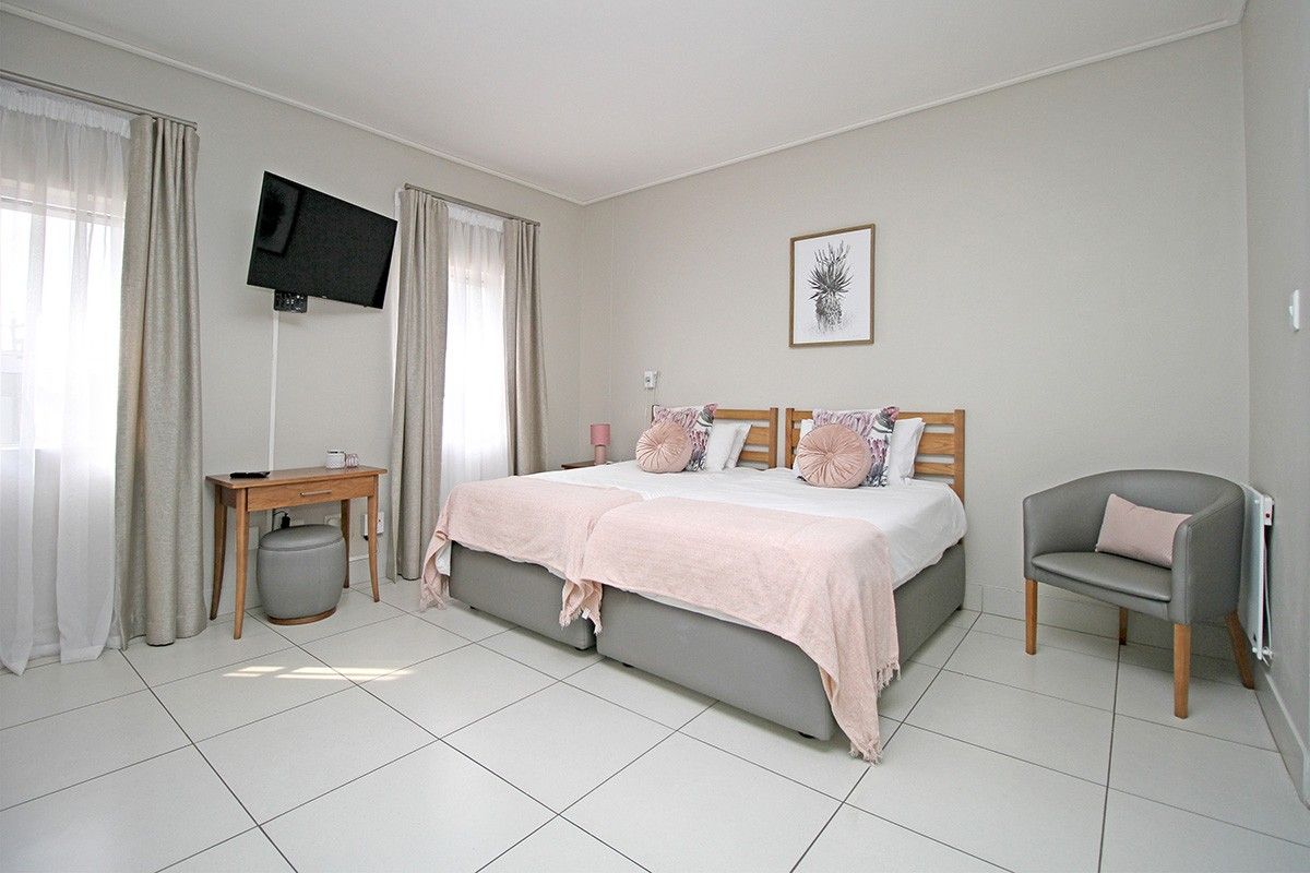 A well-maintained bedroom featuring neutral tiled flooring, wall-mounted television bracket, and an electric wall heater.