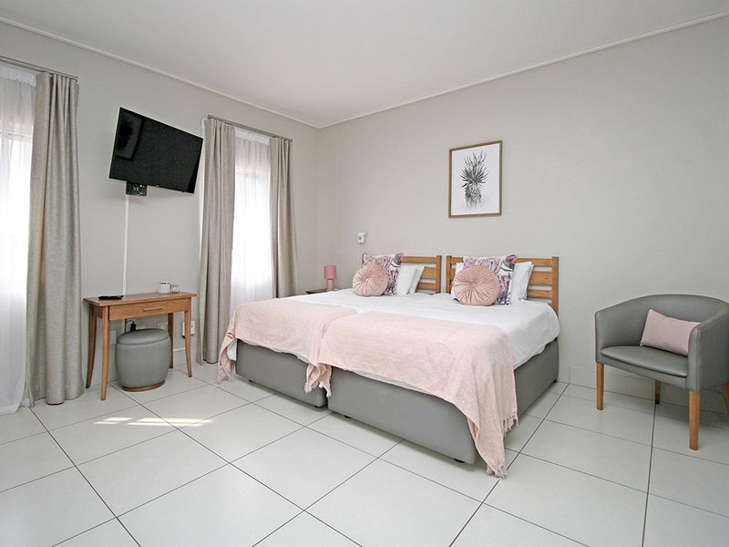 A well-maintained bedroom featuring neutral tiled flooring, wall-mounted television bracket, and an electric wall heater.