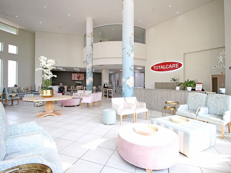 Spacious and modern retirement village clubhouse reception area featuring high ceilings, decorative columns, and a professional service desk.