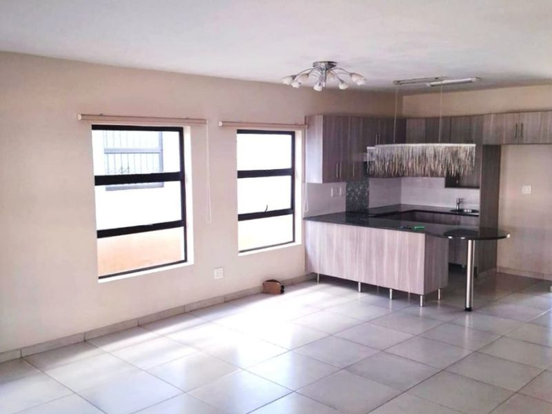 Spacious open-plan living area featuring tiled floors and a modern kitchen with built-in cabinetry, granite countertops, and a breakfast bar.