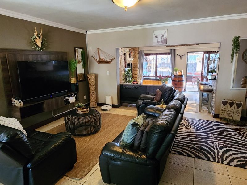 Spacious open-plan living area featuring tiled flooring, a built-in media unit, and direct access to an outdoor patio space.