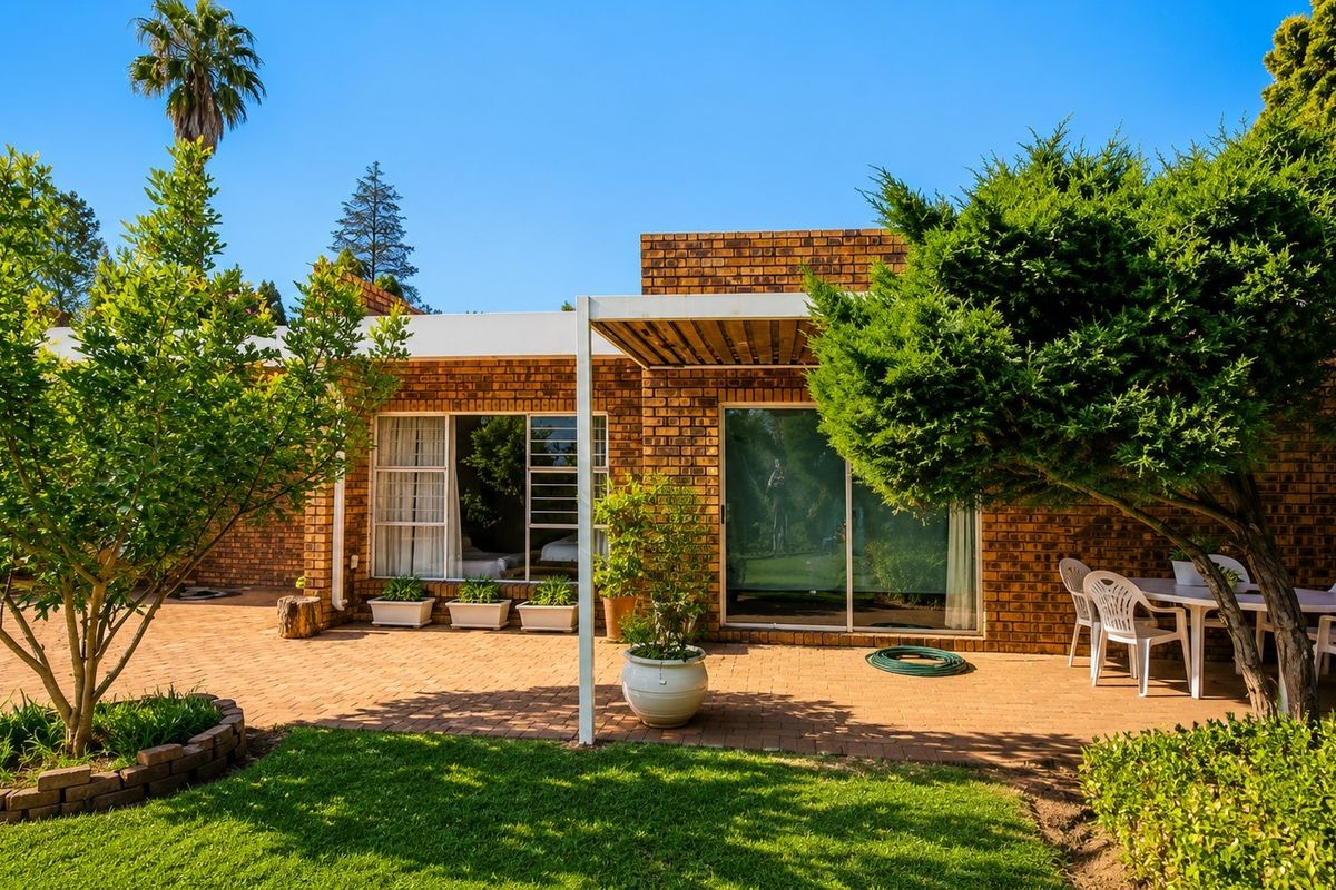 A well-maintained rear exterior view featuring a brick facade, a paved patio area with a pergola, and access through sliding glass doors.