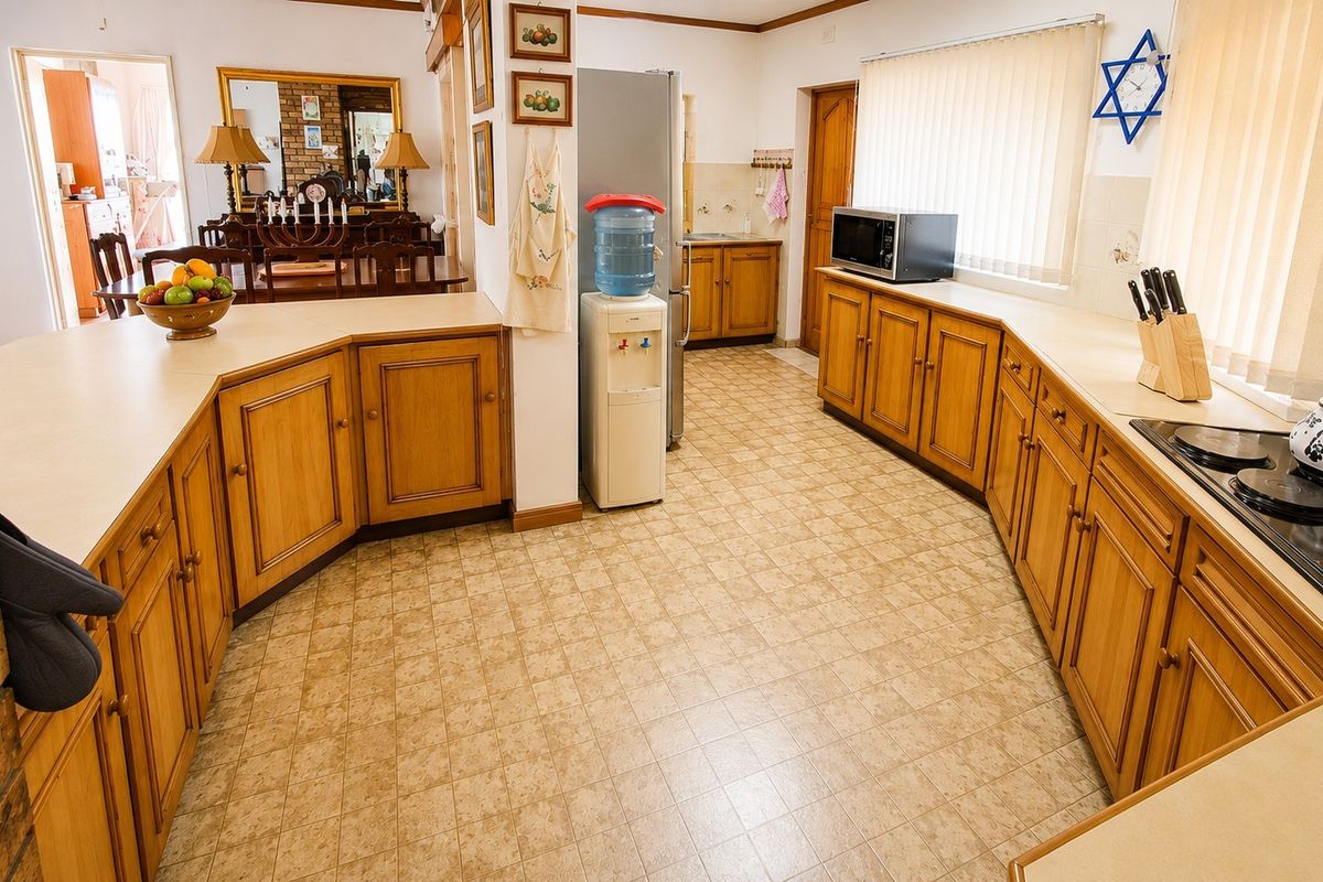Spacious kitchen featuring traditional wooden cabinetry, laminate countertops, and a built-in electric hob, offering a functional layout with ample storage space.