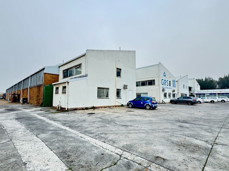 Industrial property exterior featuring a large concrete yard, multiple building facades, and functional industrial infrastructure.