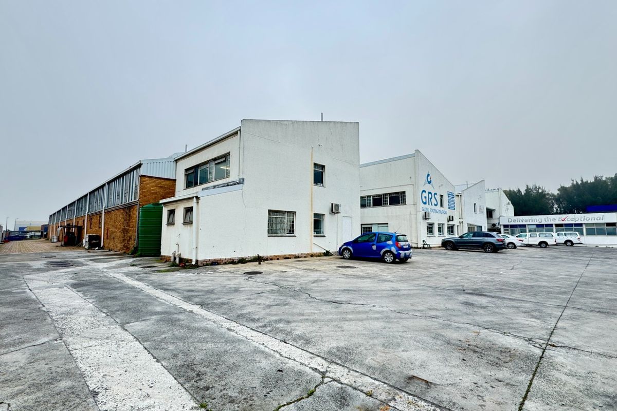 Industrial property exterior featuring a large concrete yard, multiple building facades, and functional industrial infrastructure.