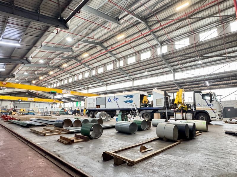 Spacious industrial warehouse facility featuring high ceilings with exposed steel trusses, overhead gantry crane, and durable concrete flooring suitable for heavy operations.