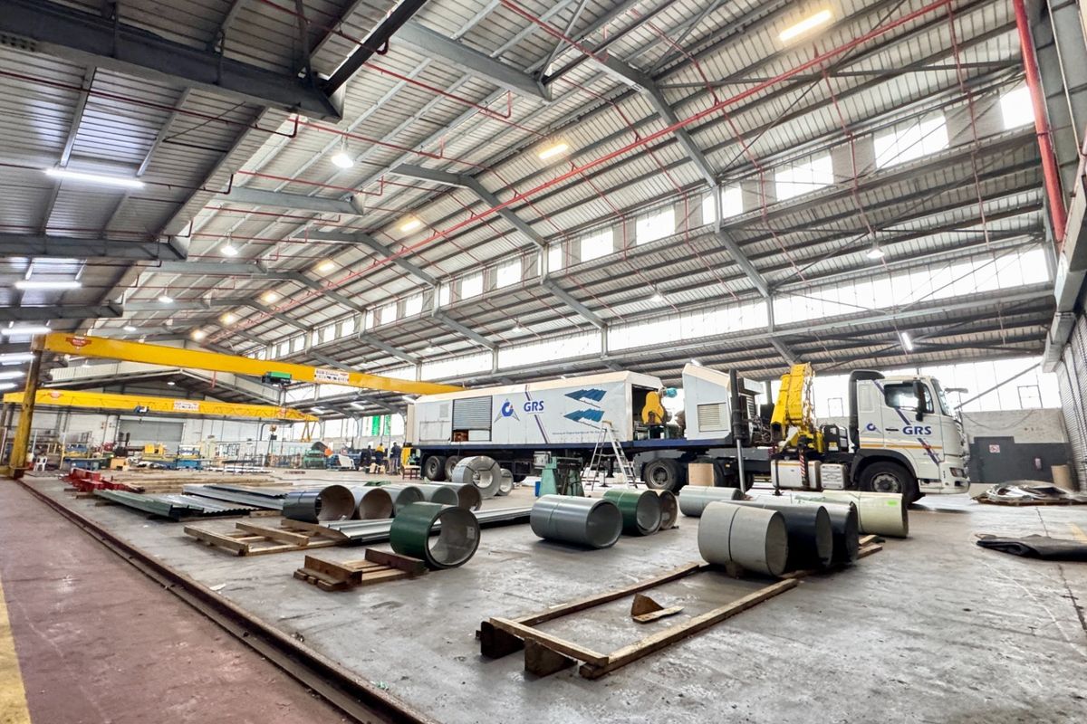 Spacious industrial warehouse facility featuring high ceilings with exposed steel trusses, overhead gantry crane, and durable concrete flooring suitable for heavy operations.
