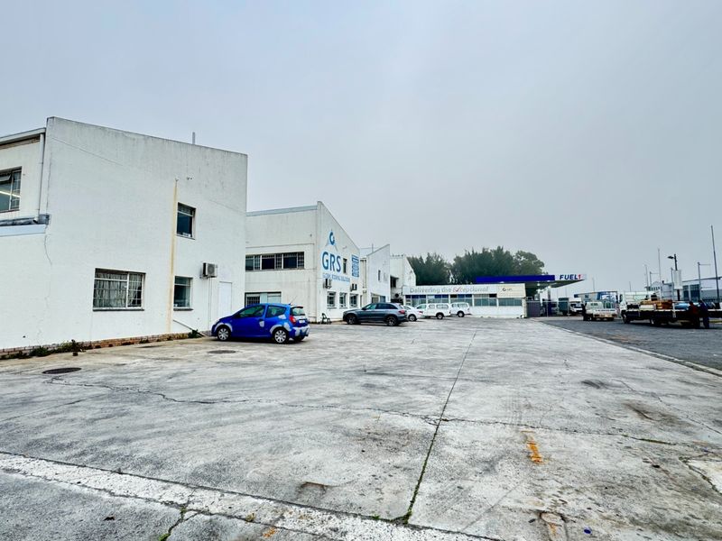 Industrial property exterior featuring a large concrete yard area and multi-unit warehouse facade with perimeter fencing.
