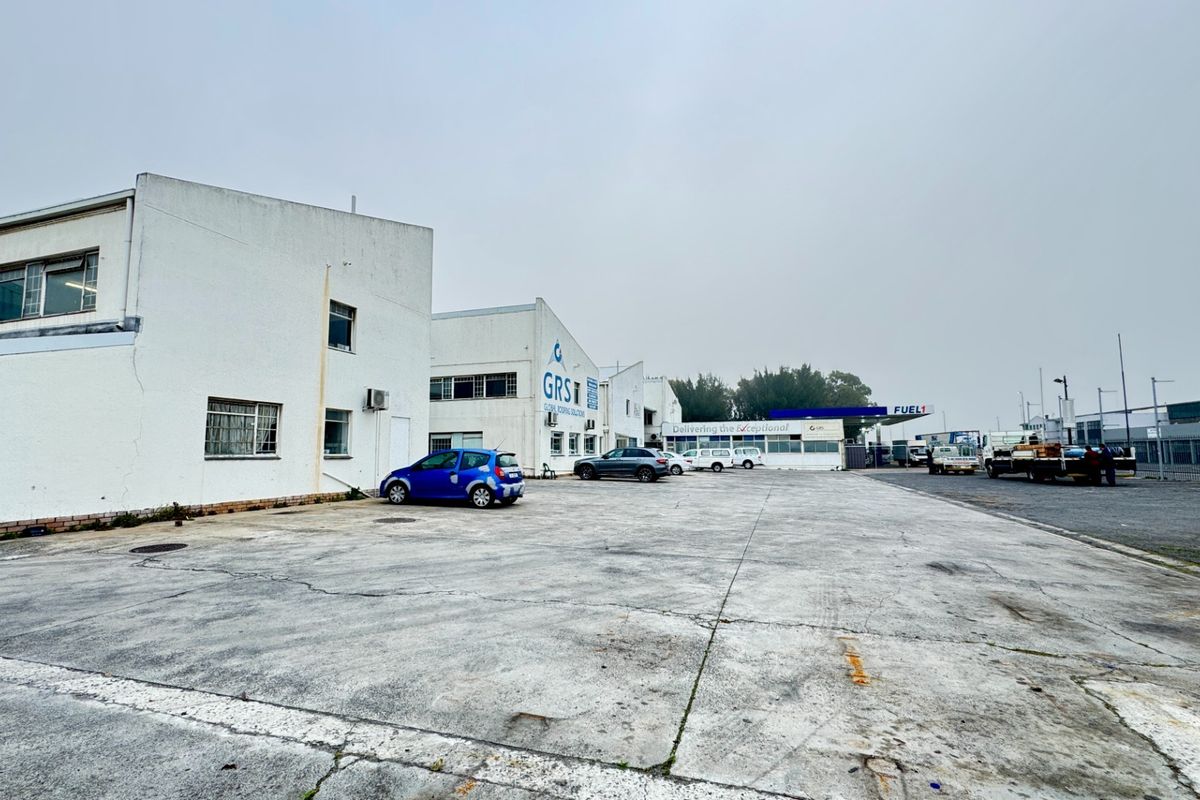 Industrial property exterior featuring a large concrete yard area and multi-unit warehouse facade with perimeter fencing.