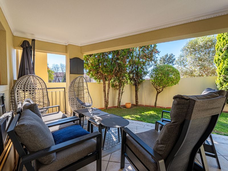 A covered patio area featuring tiled flooring and direct access to a private garden space, ideal for outdoor relaxation.