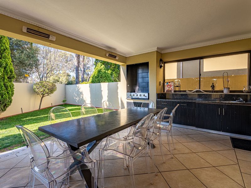 Covered patio featuring a built-in braai, granite-topped cabinetry, and tiled flooring, overlooking a private garden area.