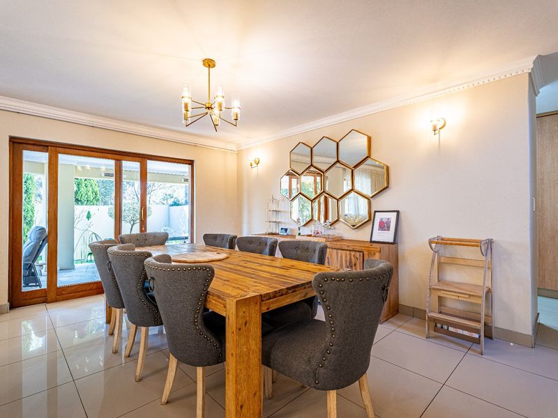 Spacious dining room featuring polished porcelain floor tiles, crown molding, and large sliding glass doors providing seamless access to the outdoor patio area.