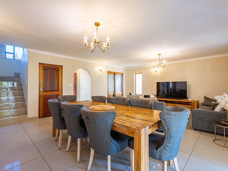 Spacious open-plan living and dining area featuring large format floor tiles, a staircase, and elegant architectural archways connecting the living spaces.