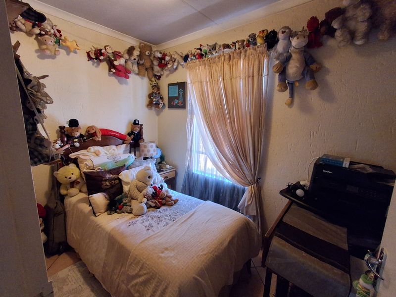 A compact bedroom featuring tiled flooring and a window with curtain treatments, offering a functional space for a single bed.