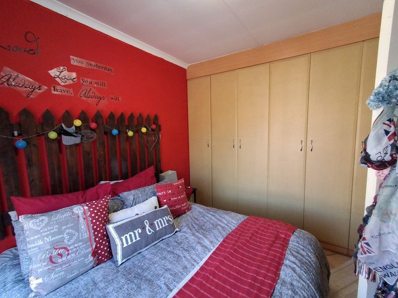 A bedroom featuring built-in cupboards and a red accent wall.