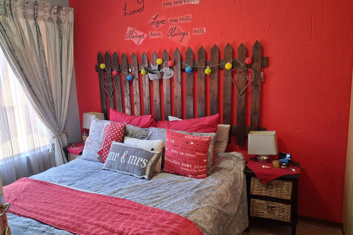 A bedroom featuring a bold red accent wall and tiled flooring, offering a functional space ready for a modern aesthetic update.