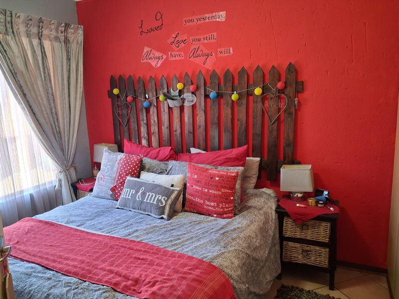 A bedroom featuring a bold red accent wall and tiled flooring, offering a functional space ready for a modern aesthetic update.