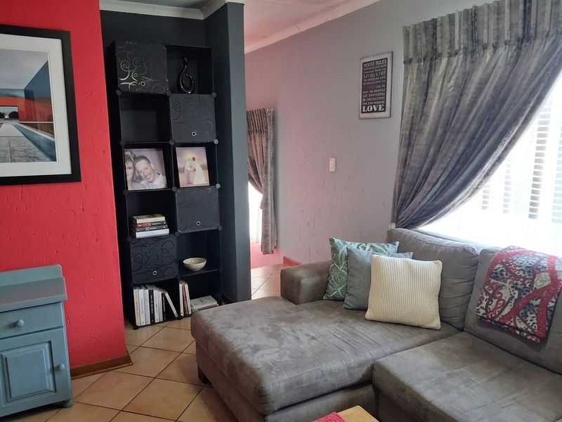 A living room featuring tiled flooring and a coved ceiling, with a bold red accent wall and neutral grey wall tones.