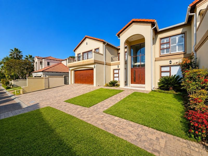 A well-maintained double-story residence featuring a paved driveway, double garage, landscaped garden, and an impressive double-volume entrance with a balcony.