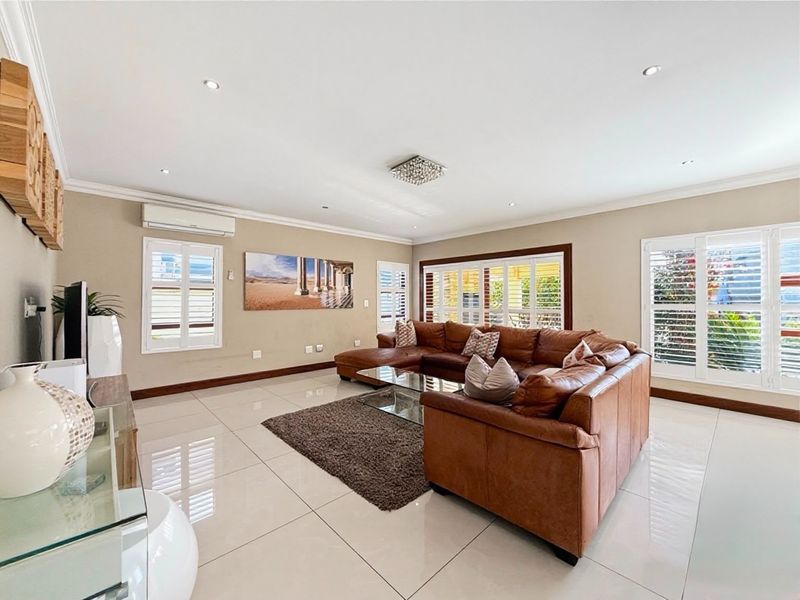 Spacious living room featuring polished porcelain floor tiles, plantation shutters, and a split-system air conditioner, offering a bright and well-maintained living environment.