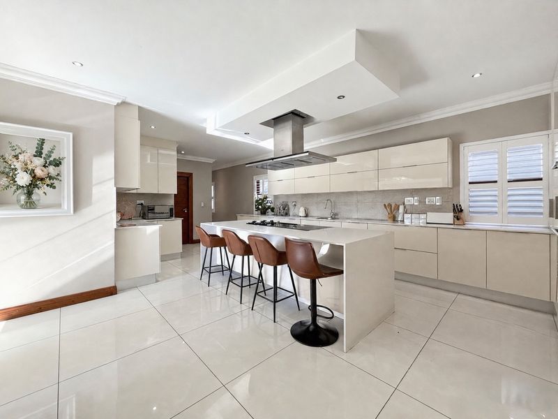 Modern, high-end kitchen featuring a large central island with gas hob, sleek gloss cabinetry, stone countertops, and polished porcelain floor tiles.