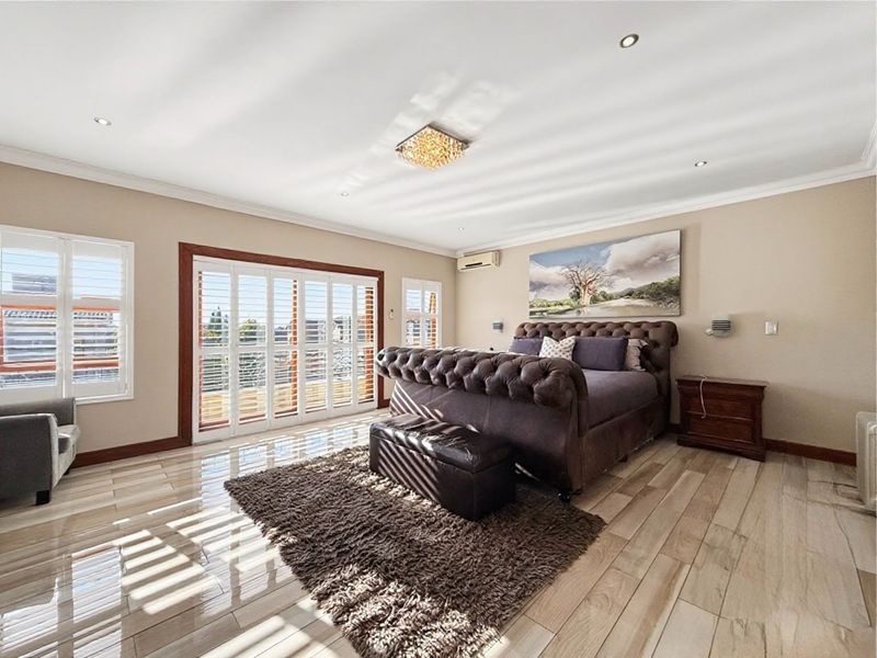 Spacious bedroom featuring tiled flooring, recessed lighting, plantation shutters, and sliding glass doors providing access to an outdoor area.