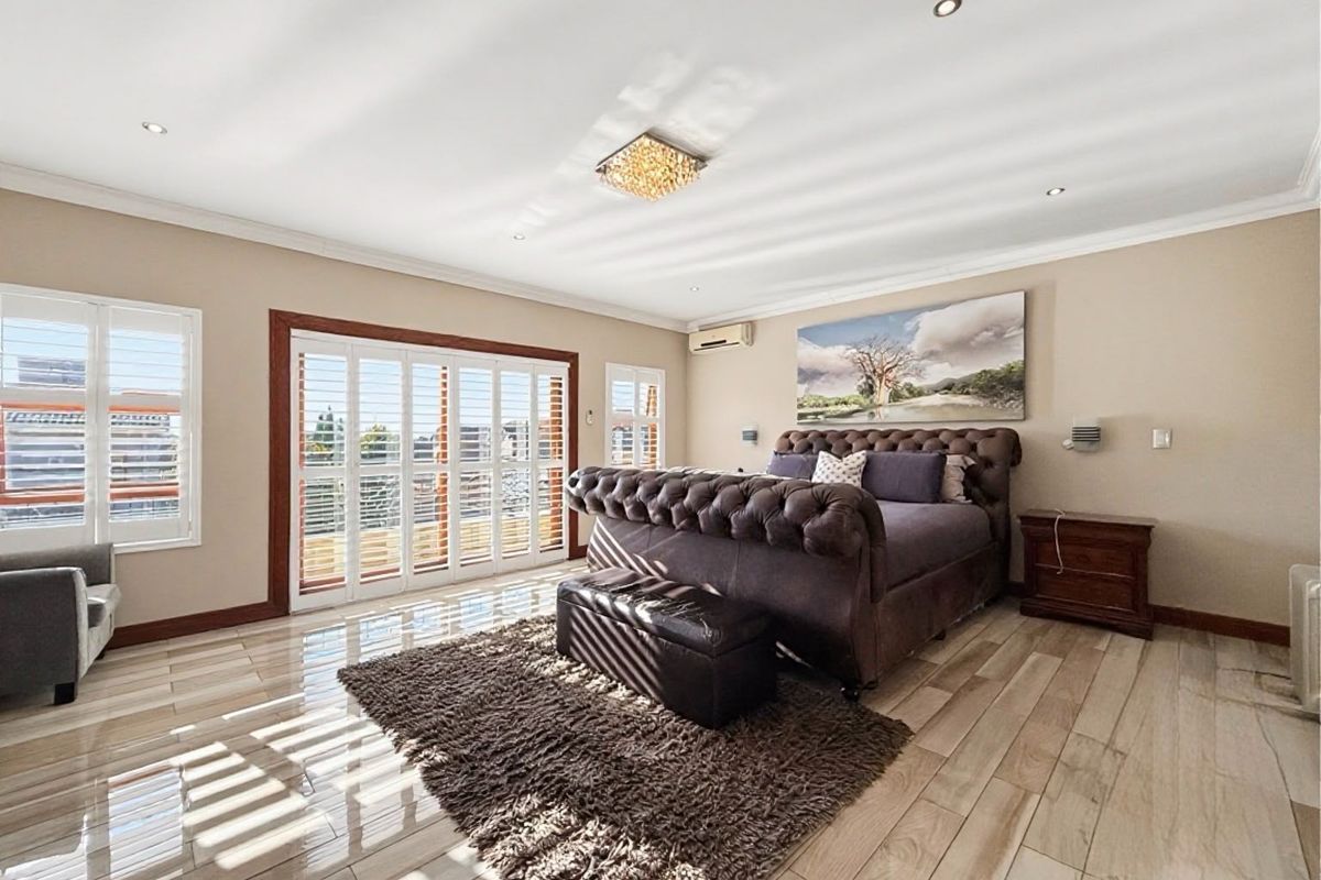 Spacious bedroom featuring tiled flooring, recessed lighting, plantation shutters, and sliding glass doors providing access to an outdoor area.