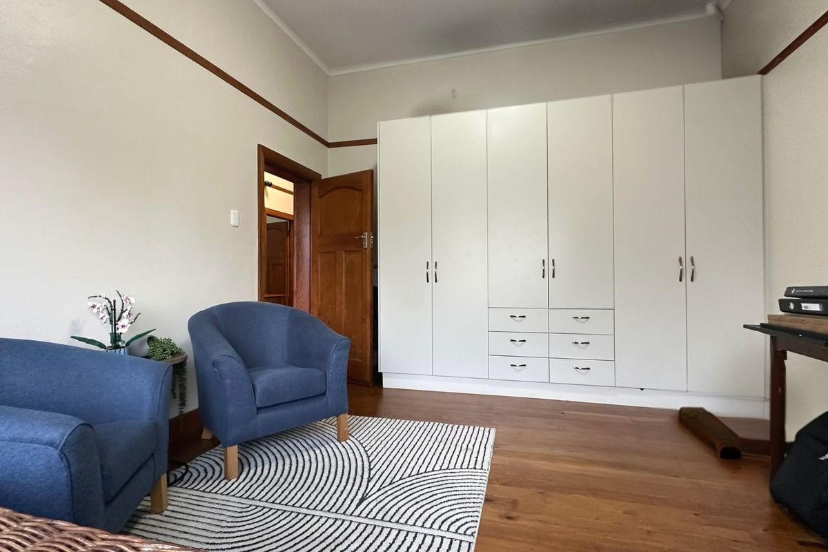 A well-maintained bedroom featuring polished timber flooring, a large white built-in wardrobe, and classic picture rail detailing.