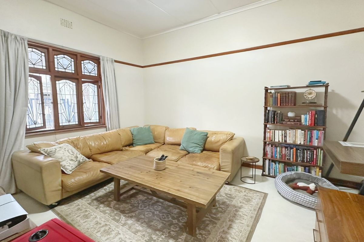 A comfortable living room featuring classic leaded glass windows, decorative picture rails, and traditional ceiling cornicing.