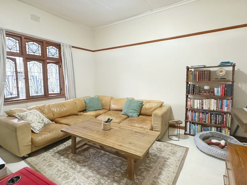A comfortable living room featuring classic leaded glass windows, decorative picture rails, and traditional ceiling cornicing.