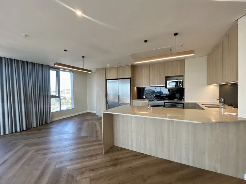 Modern open-plan living area featuring high-quality herringbone timber flooring, a sleek kitchen with stone island, integrated appliances, and floor-to-ceiling curtains.