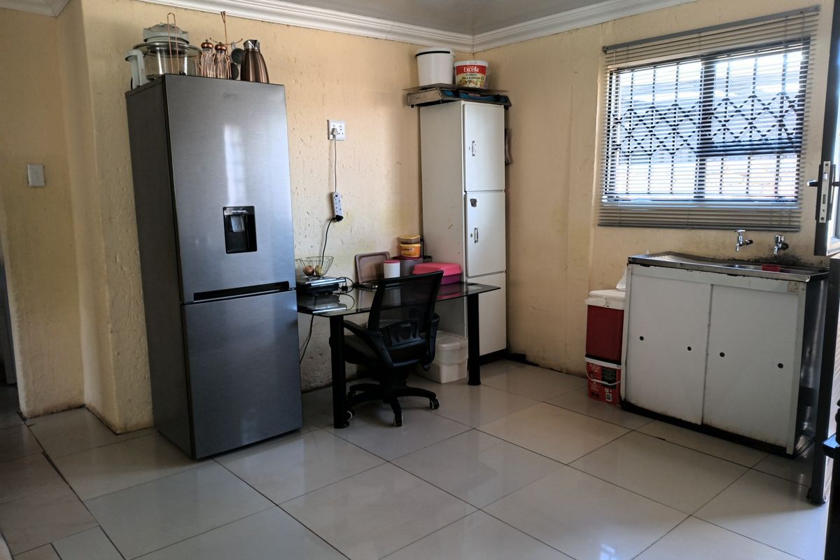 A functional kitchen area featuring tiled flooring, a stainless steel sink, and built-in cabinetry, offering potential for modernization and layout optimization.