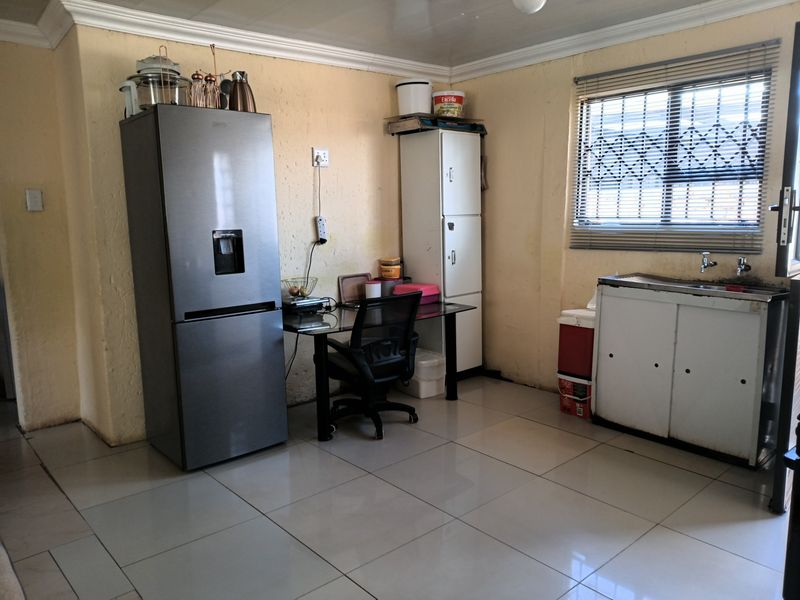 A functional kitchen area featuring tiled flooring, a stainless steel sink, and built-in cabinetry, offering potential for modernization and layout optimization.