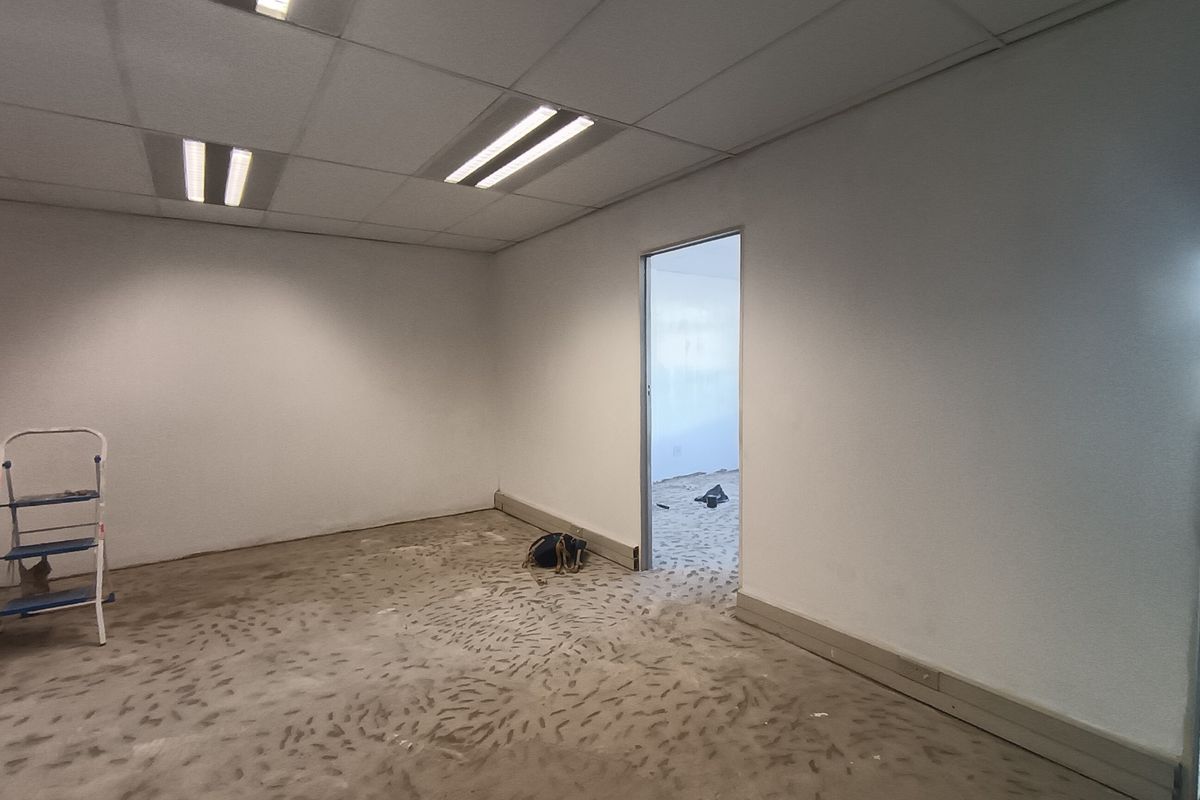An empty office space featuring a suspended ceiling with recessed lighting and unfinished concrete flooring, ready for final floor finishes.