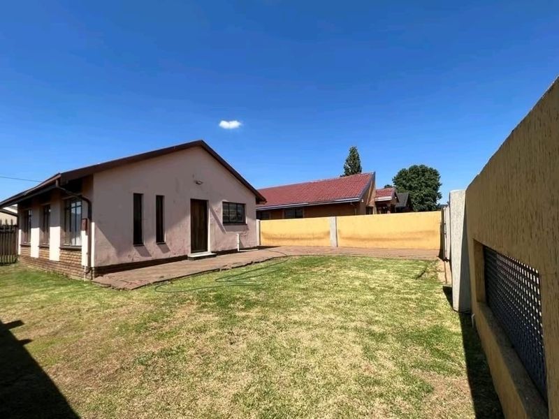 Rear view of the property featuring a private garden, paved walkway, and perimeter walling.