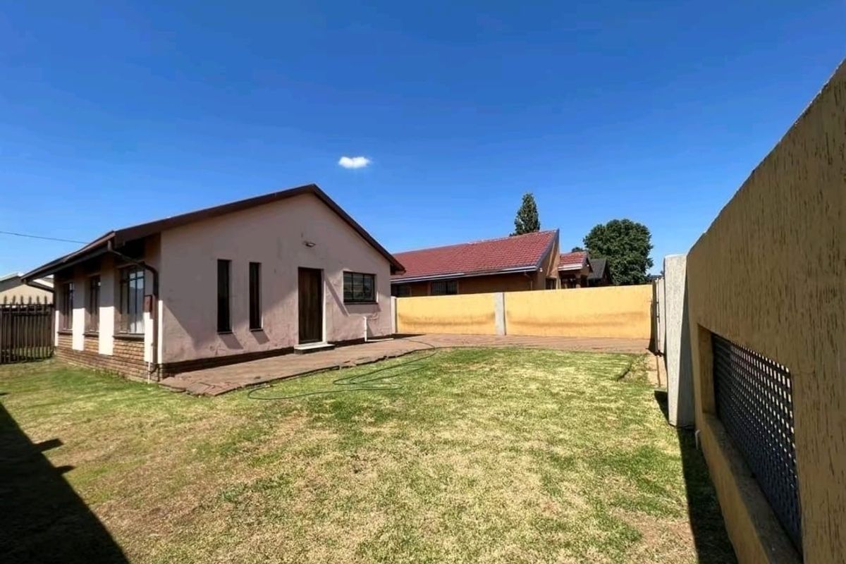 Rear view of the property featuring a private garden, paved walkway, and perimeter walling.