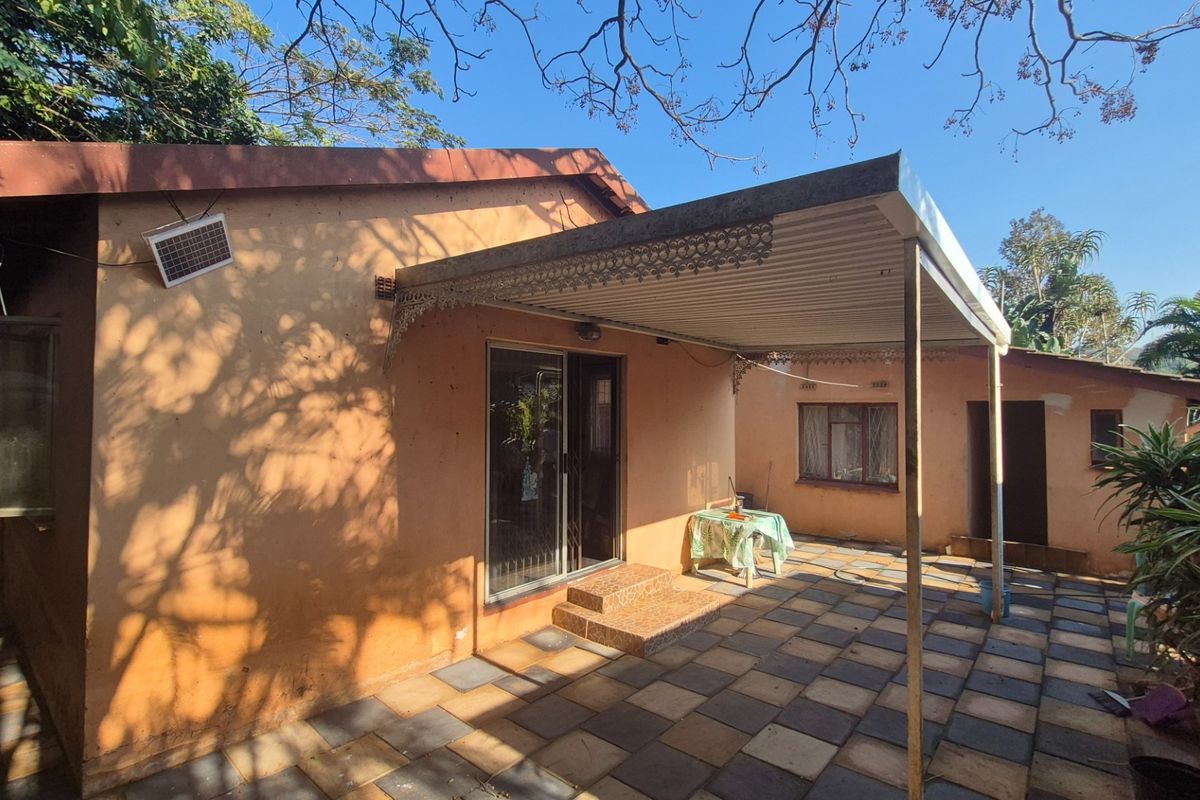 Rear exterior view featuring a covered patio area with tiled flooring, sliding door access, and a metal roof awning.