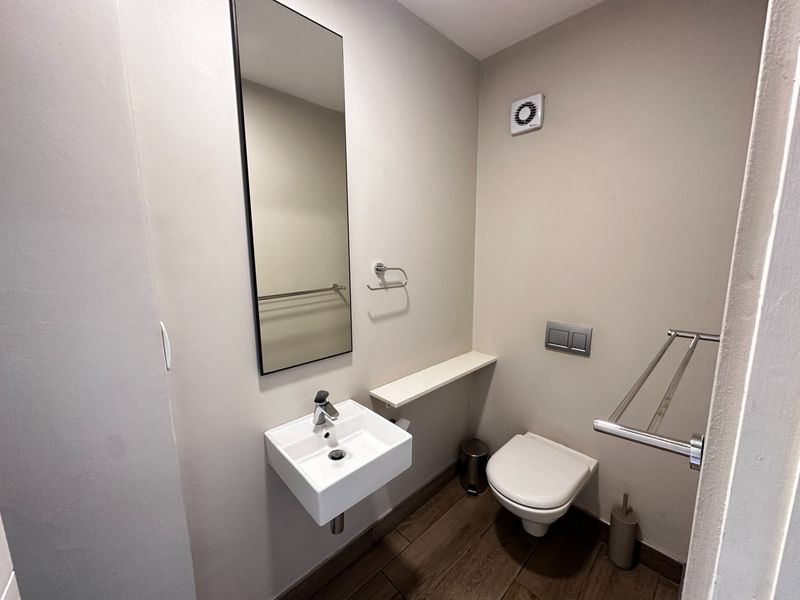 A clean and modern guest bathroom featuring a wall-mounted basin, wall-hung toilet with concealed cistern, and neutral finishes.