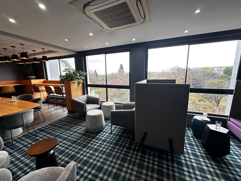 A modern, well-lit open-plan lounge area featuring large windows with scenic views, integrated air conditioning, and a built-in bar counter.