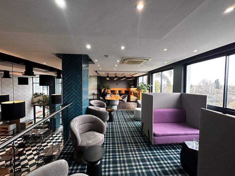 A modern open-plan communal lounge area featuring contemporary finishes, recessed lighting, ducted air conditioning, and large windows with views.