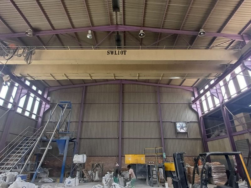 Spacious industrial warehouse featuring a high-clearance steel structure, integrated overhead bridge crane, and functional industrial ventilation systems.